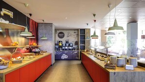 A cafe with a long counter, shelves with snacks, and a coffee station in the background. - ibis Augsburg Koenigsplatz (Augsburg)