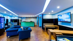 Ein stilvoller Lounge-Bereich mit Sofas, einem Holztisch und einem Fernsehbildschirm.