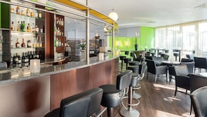 A modern bar area with a curved counter, multiple seating options, and a green accent wall.