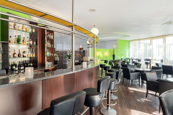 A modern bar area with a curved counter, multiple seating options, and a green accent wall.