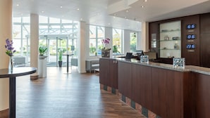 A modern reception area with a wooden reception desk, a digital clock displaying the time, and a glass display case with items.