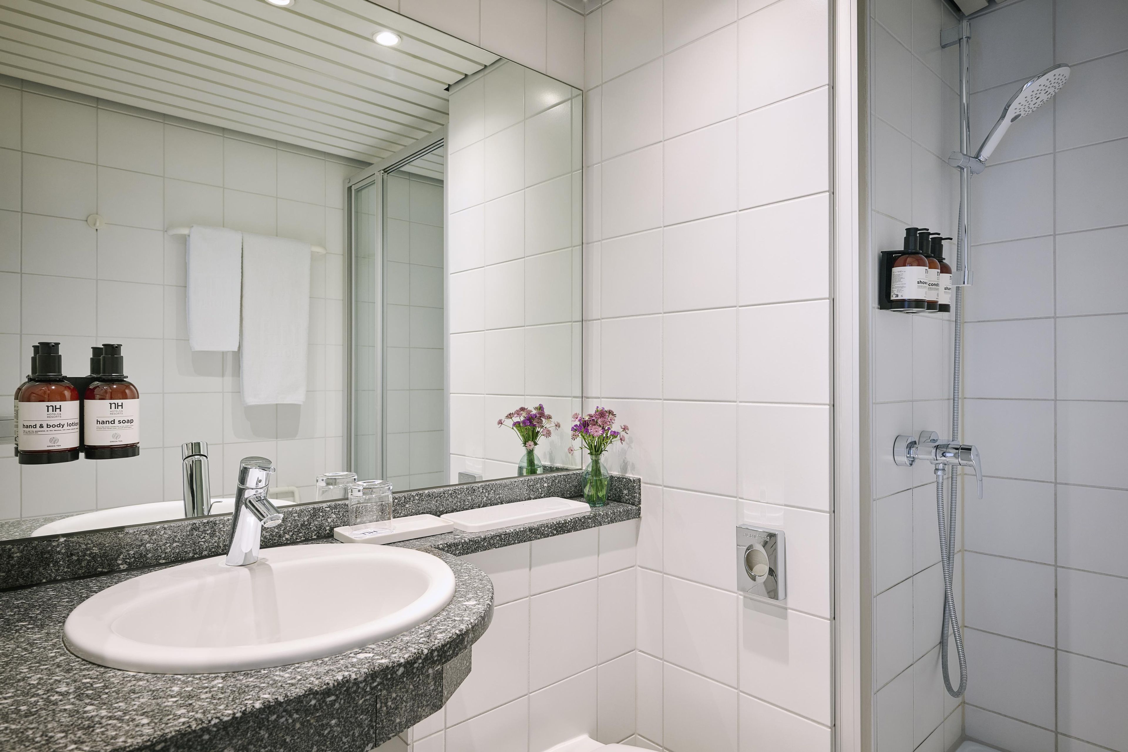Ein modernes Badezimmer mit einem Waschbecken aus Granit, einer Handbrause und einem großen Spiegel.