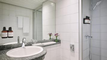 Ein modernes Badezimmer mit einem Waschbecken aus Granit, einer Handbrause und einem großen Spiegel.
