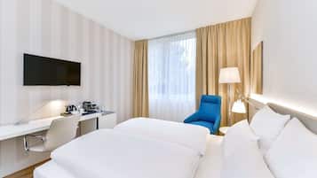 Ein Hotelzimmer mit Bett, Schreibtisch, Stuhl, Fernseher und Vorhängen.