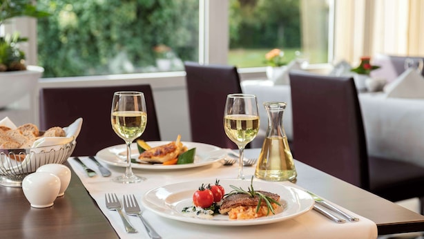 A dining table set with plates of food, wine glasses, and cutlery.
