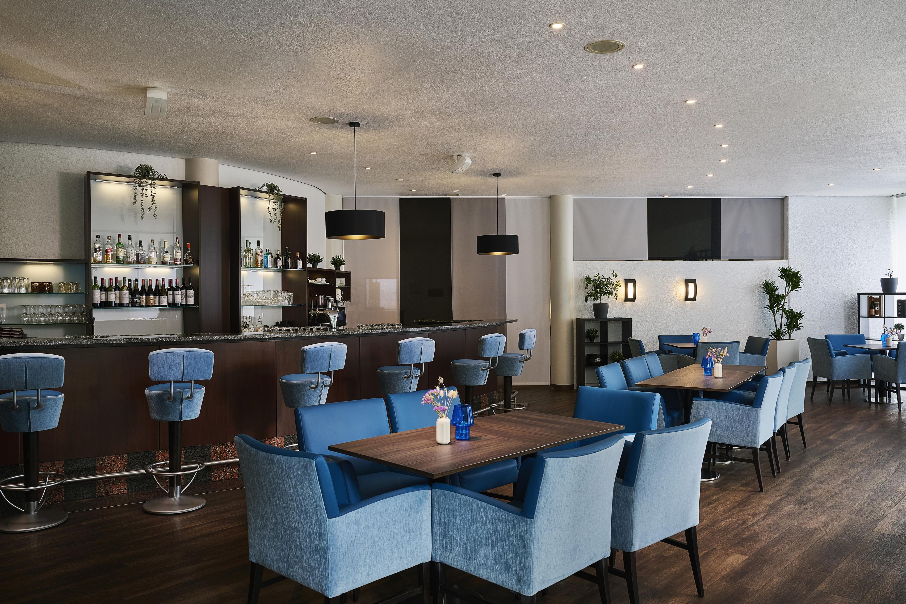 Un'area bar moderna con posti a sedere e un bancone che espone diverse bottiglie.