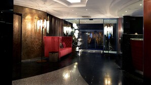 Un hall d’entrée moderne avec un canapé rouge, un lustre et une entrée en verre.