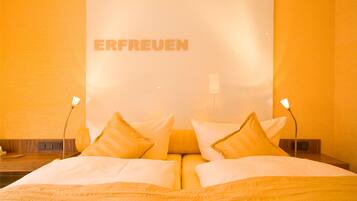 A hotel room with a bed, pillows, and a wall with the word "ERFREUEN" visible.