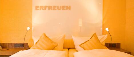 Habitación de hotel con una cama, almohadas y una pared donde se lee la palabra "ERFREUEN".