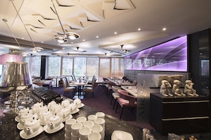 A modern restaurant interior with tables, chairs, and a bar area.