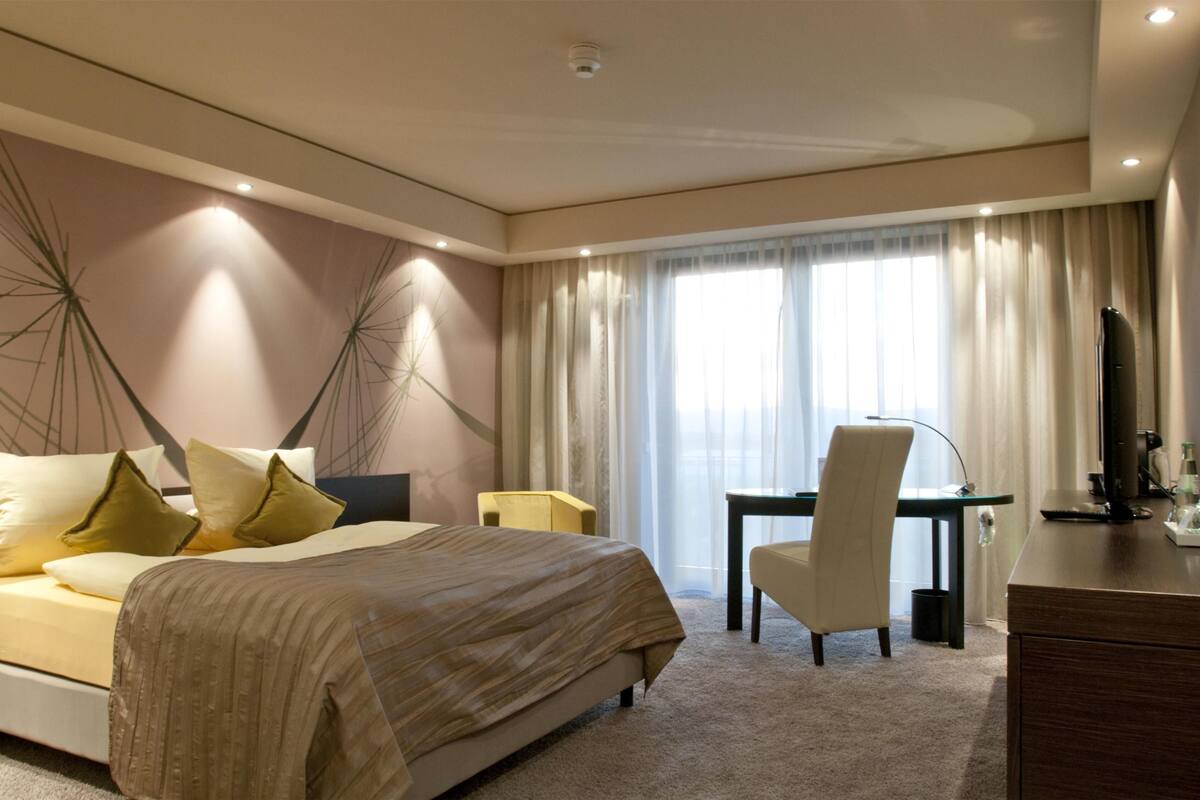 Ett hotellrum med en säng, ett skrivbord, en stol och en tv.