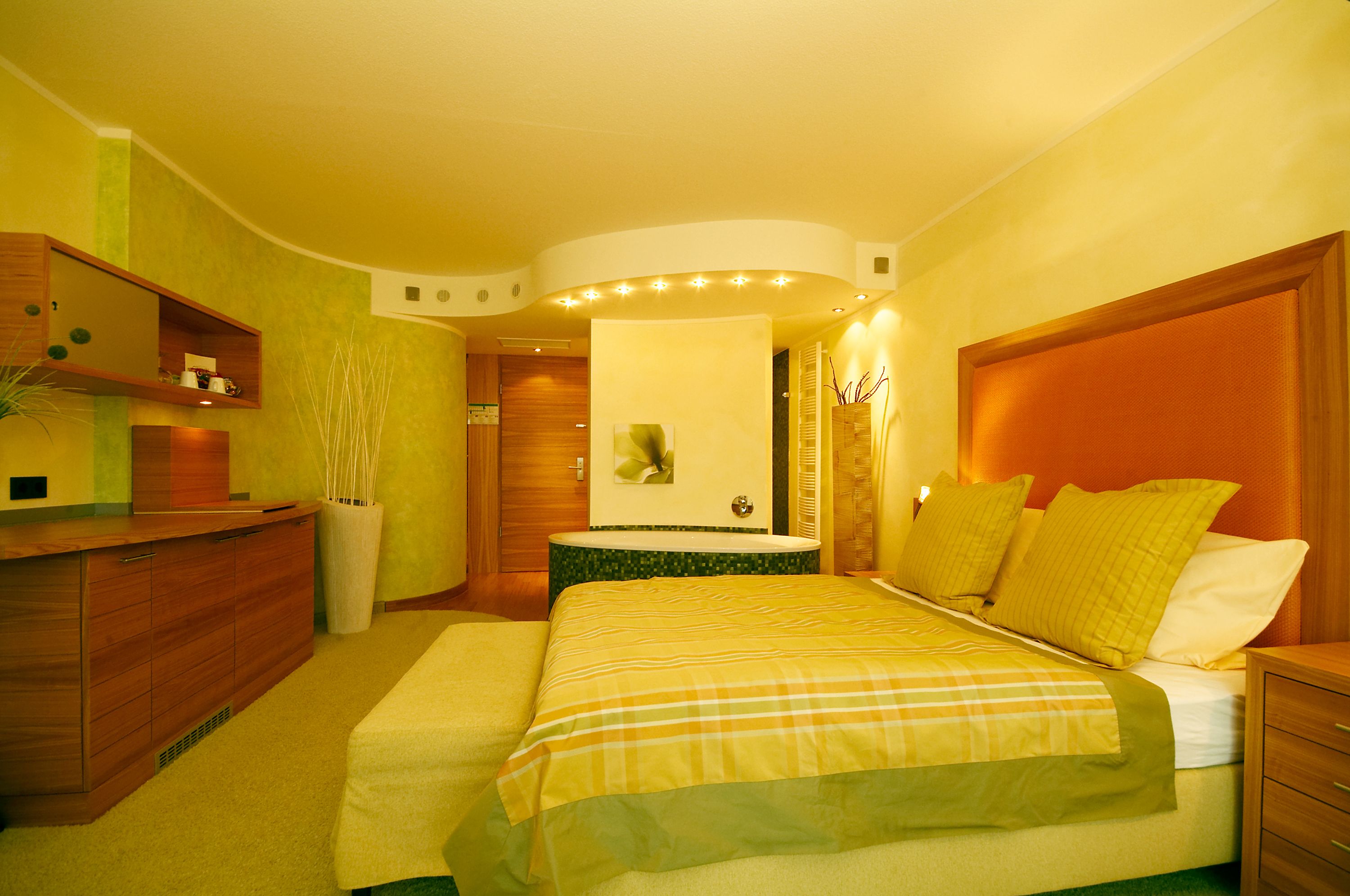 Una habitación de hotel con cama, mesita de noche y cómoda de madera.