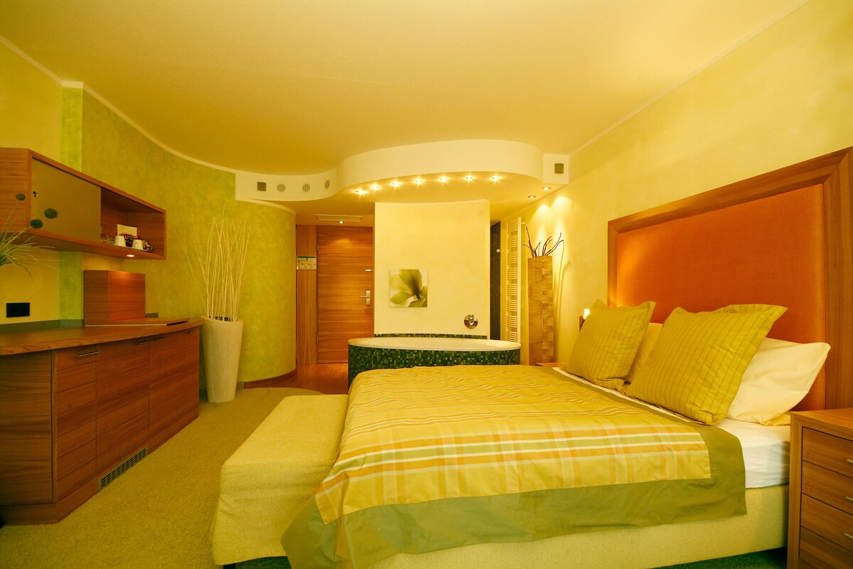 Una habitación de hotel con cama, mesita de noche y cómoda de madera.