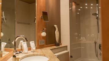 Ein modernes Badezimmer mit Waschbecken, Spiegel, Handtuchhalter und Duschbereich.