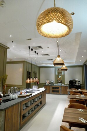 A modern hotel dining area with a central bar, multiple seating options, and decorative lighting fixtures. - Hotel Amadeus Frankfurt (Frankfurt)