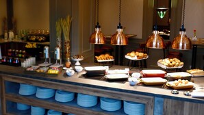 Ein Buffet mit mehreren hängenden Kupferleuchten, verschiedenen Speisen und ordentlich angeordneten blauen Tellern auf einer Holzeinrichtung.