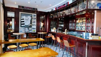 A bar area with wooden tables and chairs, a bar counter with a glass display case, and a chalkboard menu.