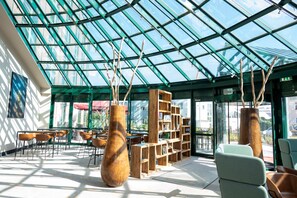 A spacious indoor area with a glass ceiling, wooden bookshelves, and seating arrangements. - Hotel Amadeus Frankfurt (Frankfurt)