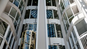 Ein mehrstöckiges Atrium mit Glasdecke und weißen Wänden.