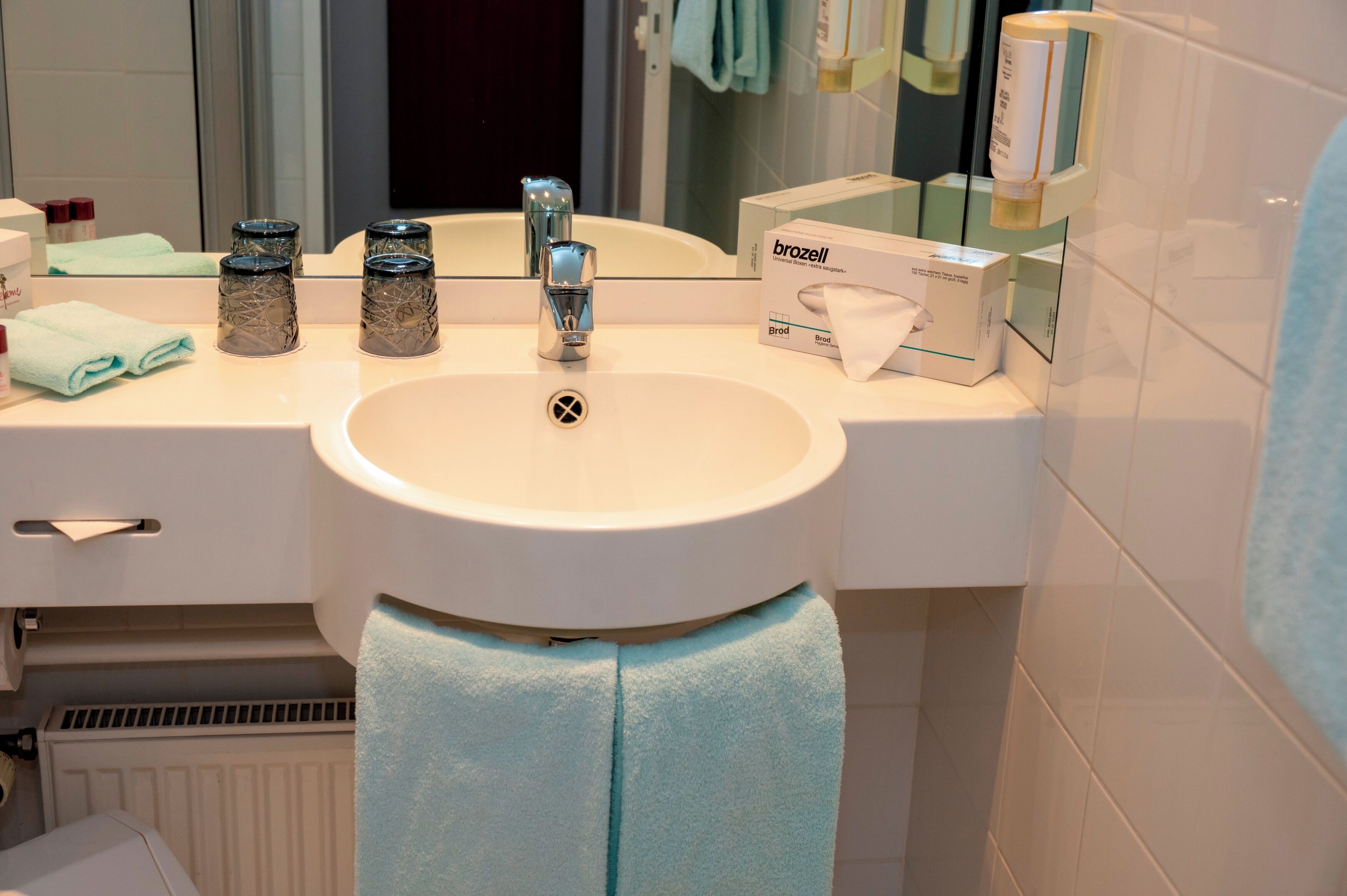 A bathroom with a sink, mirror, and toiletries.