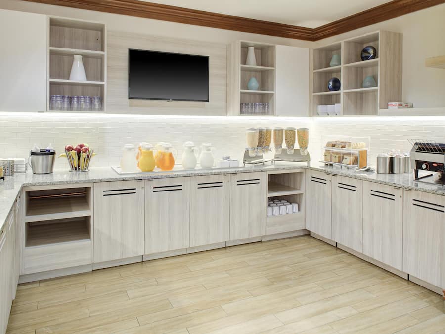 A modern kitchen with built-in appliances, a flat-screen TV, and a variety of storage cabinets.