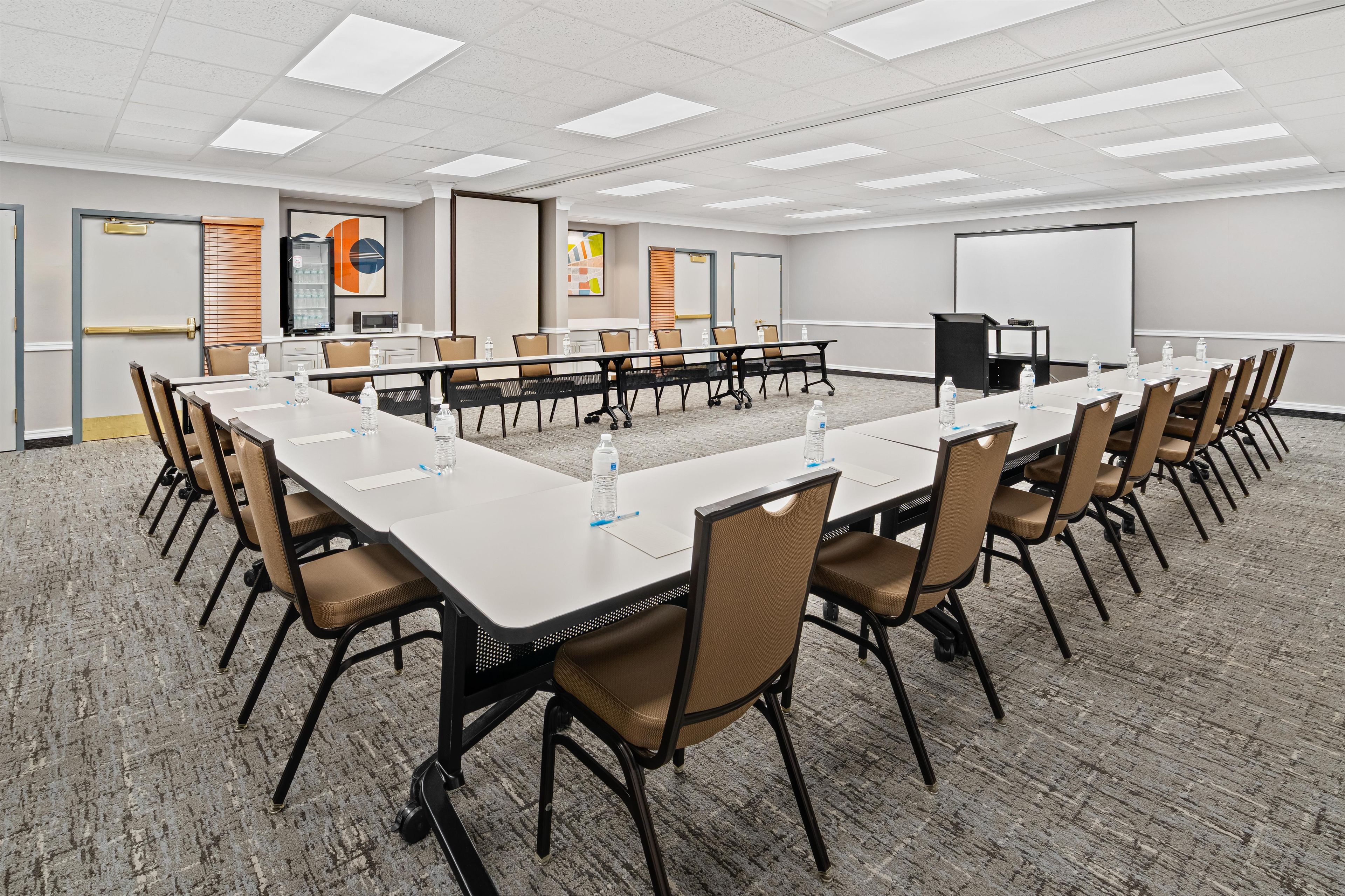 A conference room with a long table, chairs, a projector screen, and a whiteboard.