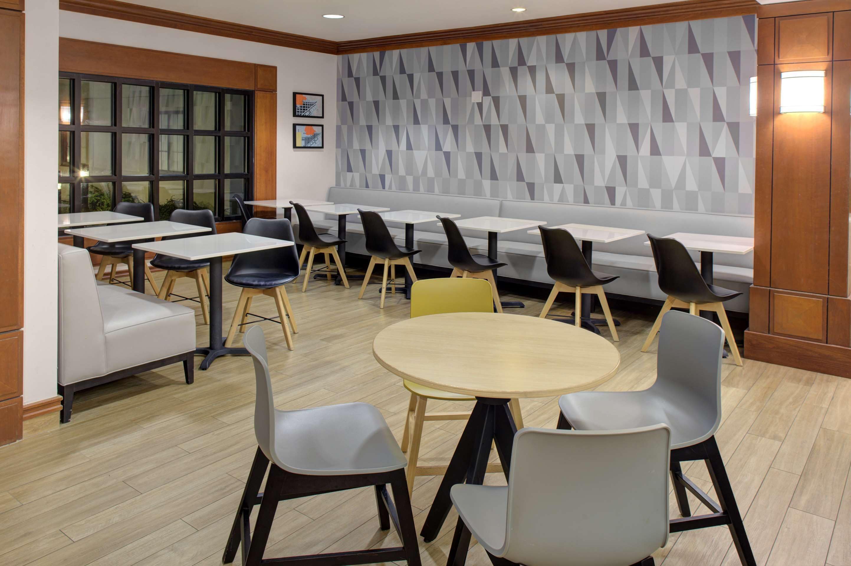 A modern dining area with a mix of seating options including tables, chairs, and a bench.