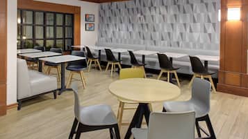 A modern dining area with a mix of seating options including tables, chairs, and a bench.