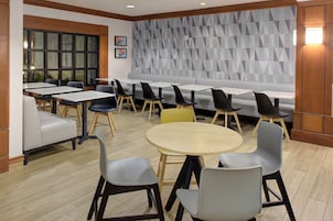 Un comedor moderno con diversas opciones de asiento, incluyendo mesas, sillas y un banco.