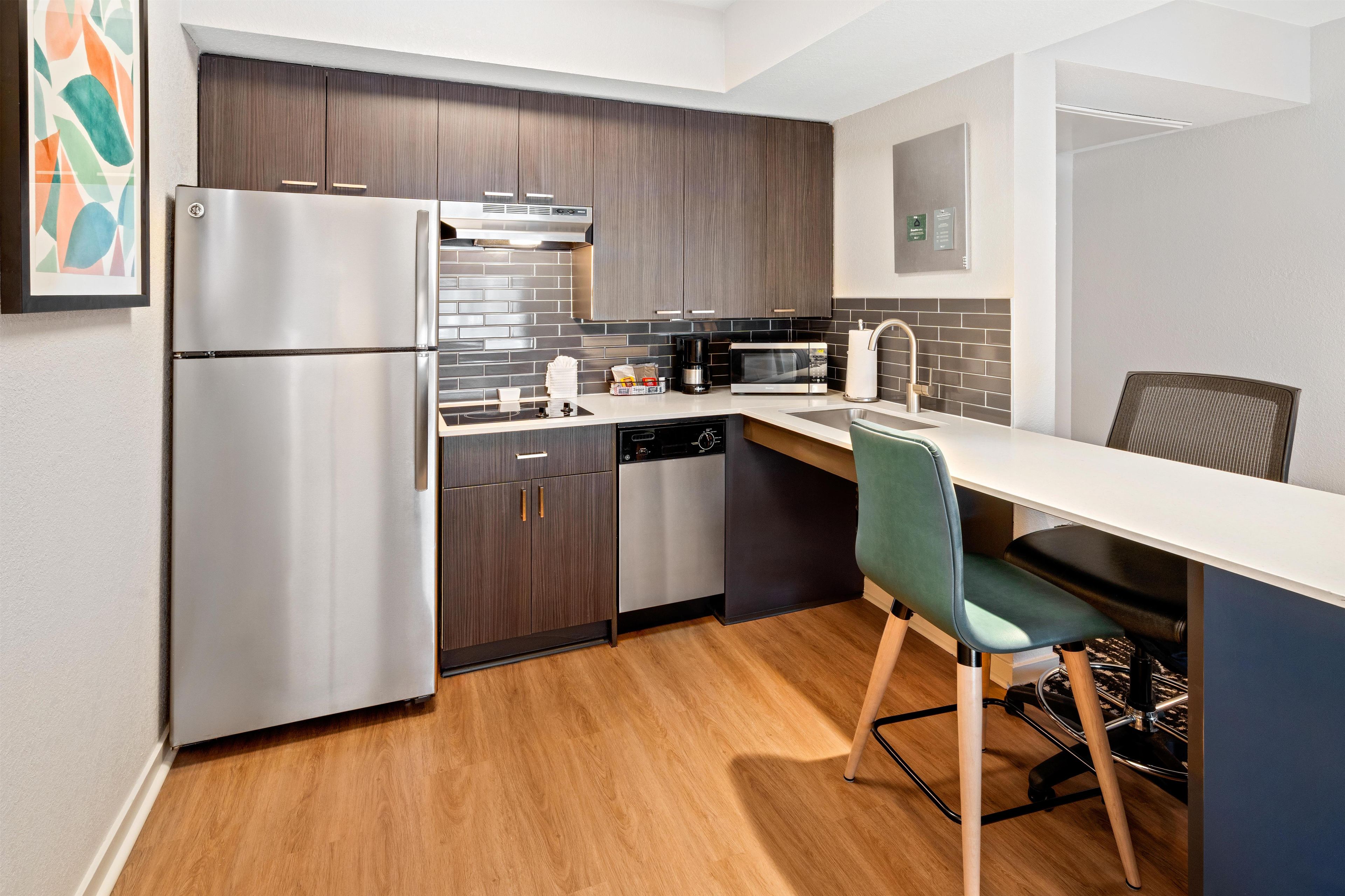 A modern kitchen with a refrigerator, microwave, and dishwasher.