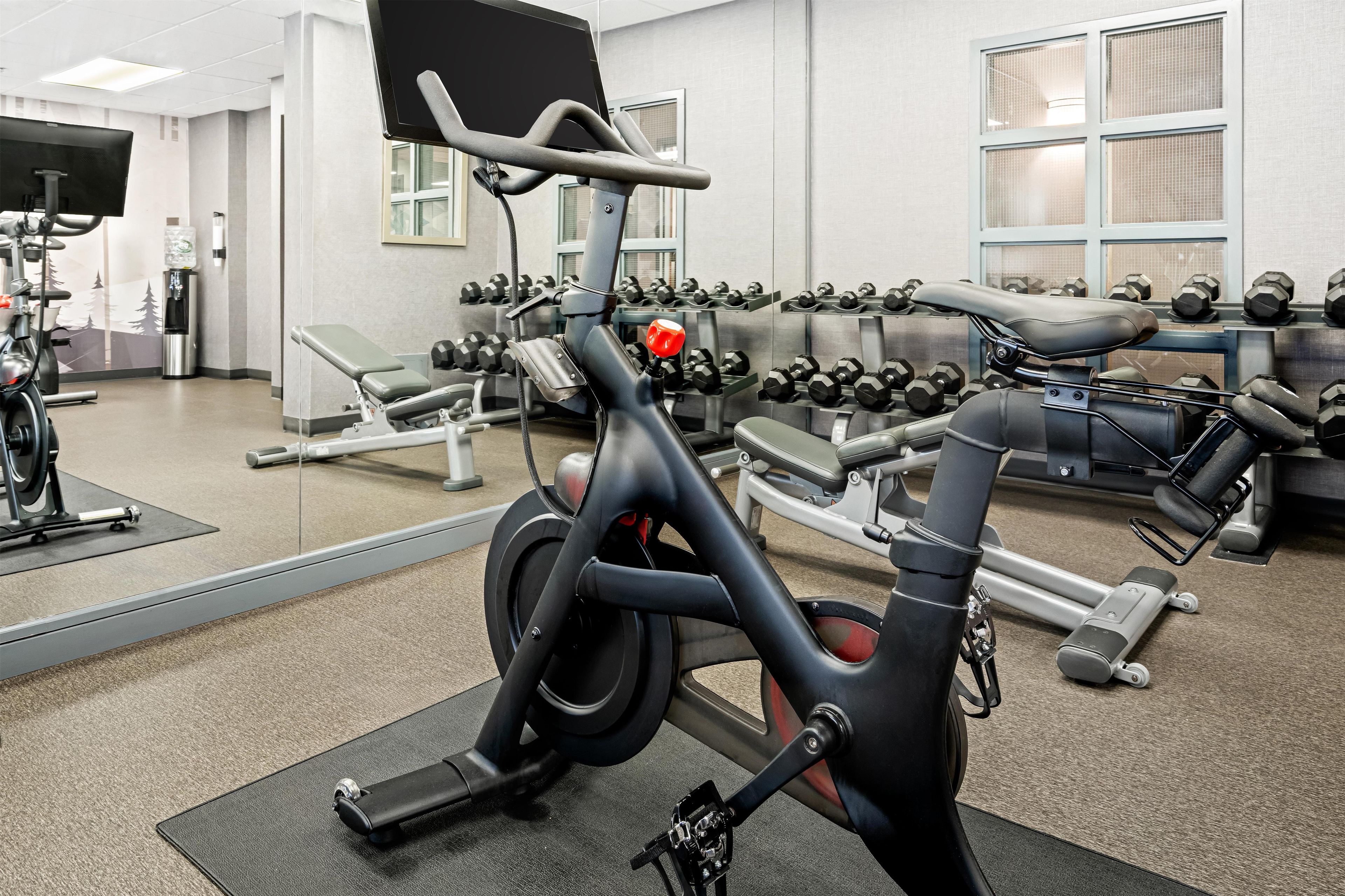 Ett gym med träningsutrustning, en vattenautomat och en spegel.