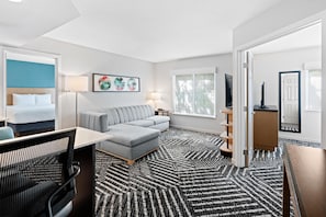 A hotel room with a bed, a sofa, a desk, a chair, a TV, a lamp, a bookshelf, and a window. - HYATT house Boston/Burlington (Burlington)