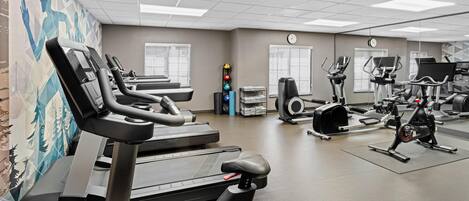 A gym with treadmills, elliptical machines, and weight equipment.