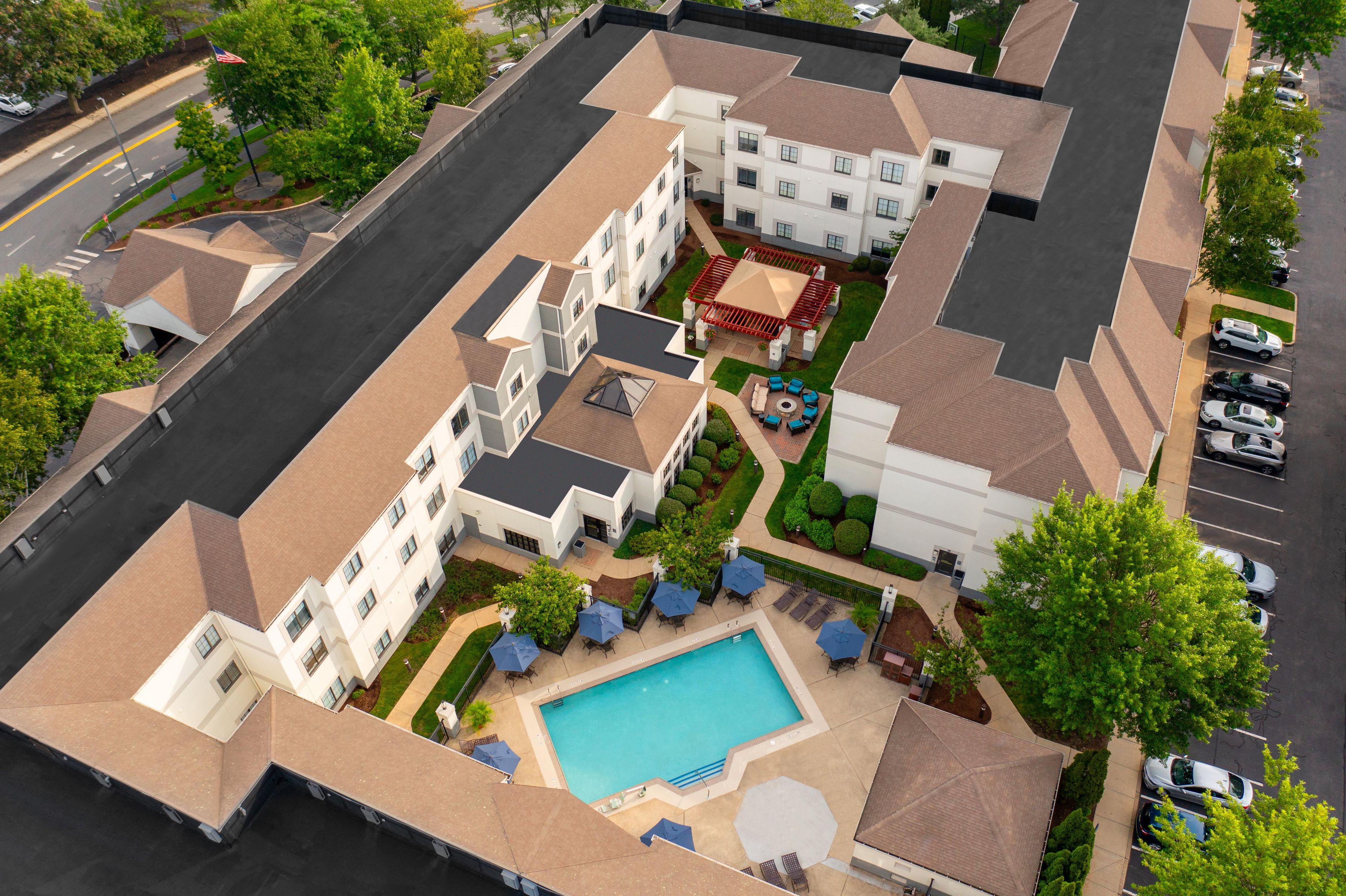An aerial view of a residential complex with a swimming pool, multiple buildings, and a parking area.
