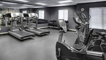A gym with treadmills, elliptical machines, and dumbbells.