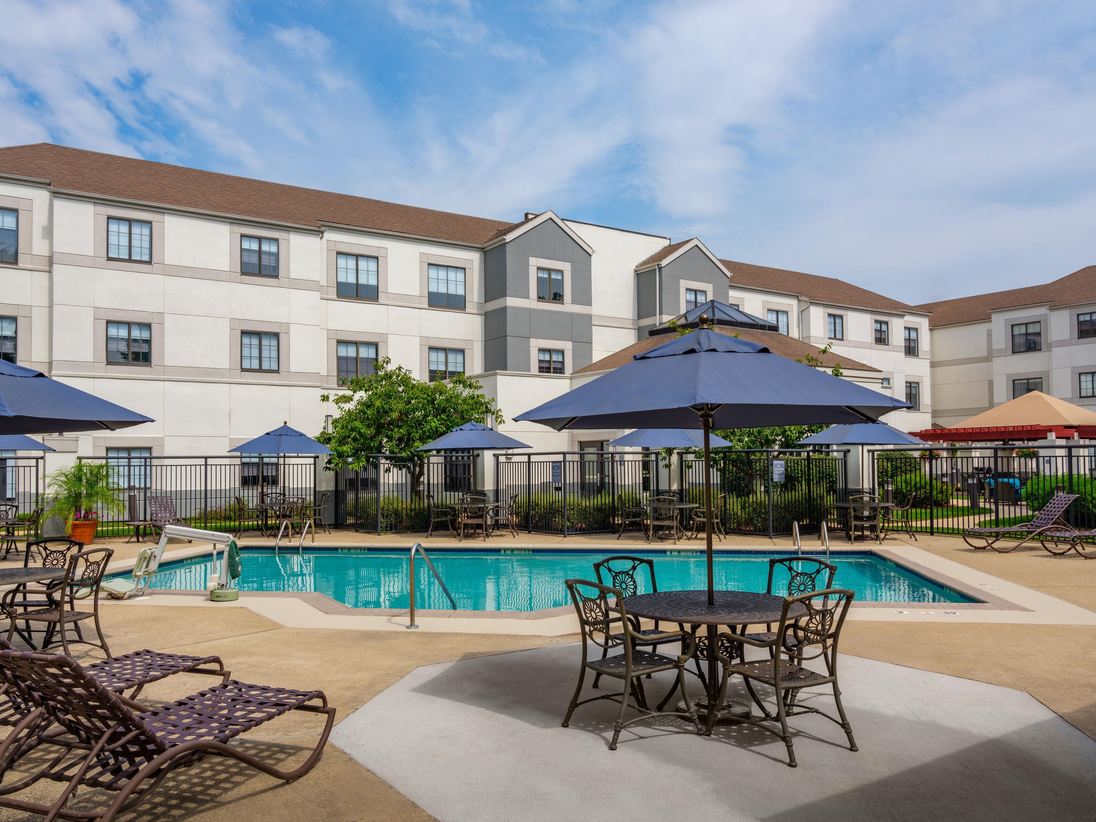 A poolside area with lounge chairs, umbrellas, and a pool.