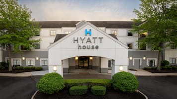A Hyatt House hotel entrance with a modern design, including a prominent 'H' logo, a gated entrance, and well-maintained landscaping.