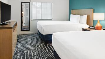 A hotel room with two beds, a television, a desk, and a lamp.