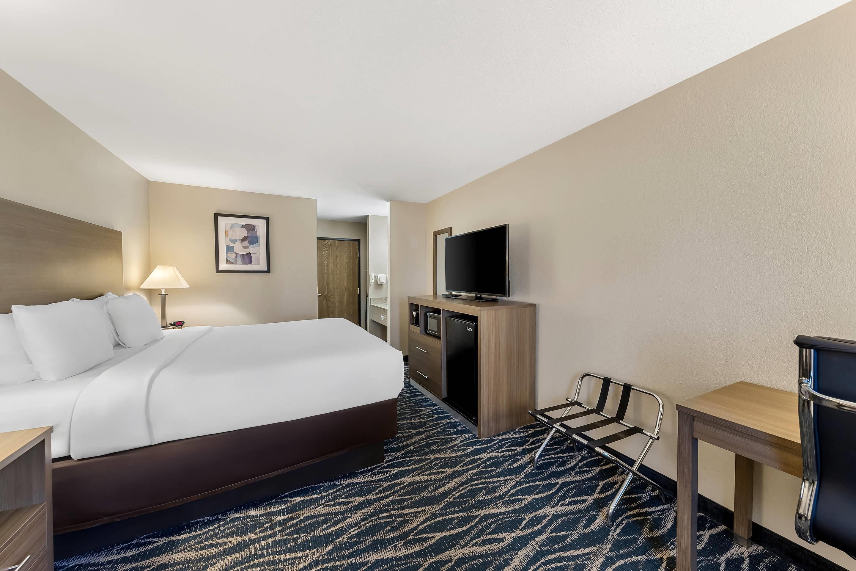 Une chambre d’hôtel avec un lit, un bureau, une télévision et une chaise.