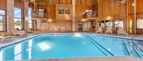 A large indoor swimming pool with wooden walls and multiple levels of balconies.