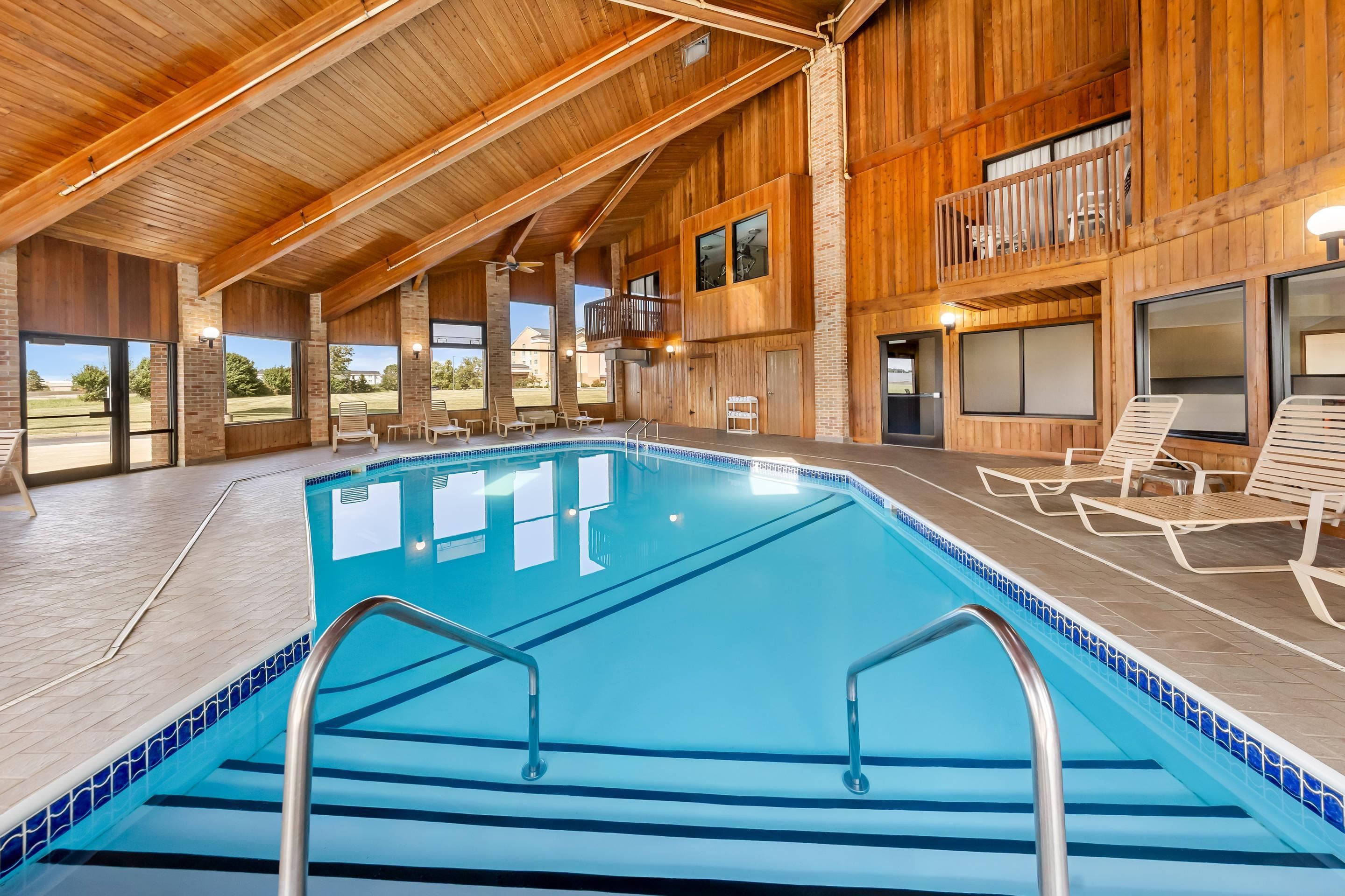 A large indoor swimming pool with clear blue water, surrounded by wooden walls and large windows.