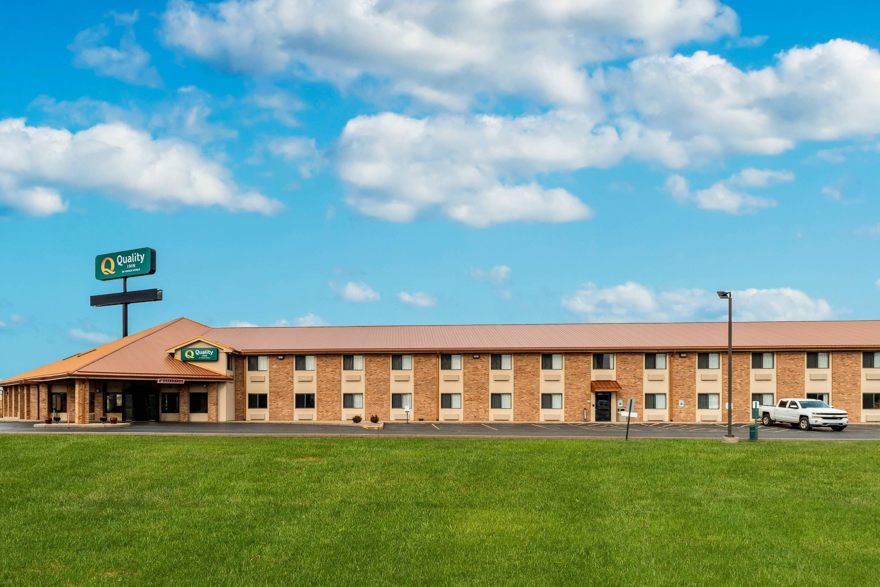 A Quality Inn hotel with a brick facade, a clear sky, and a parking lot.