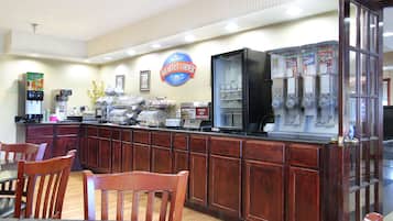 A breakfast bar with a sign reading "Breakfast Corner," a coffee machine, a refrigerator with beverages, and a microwave.