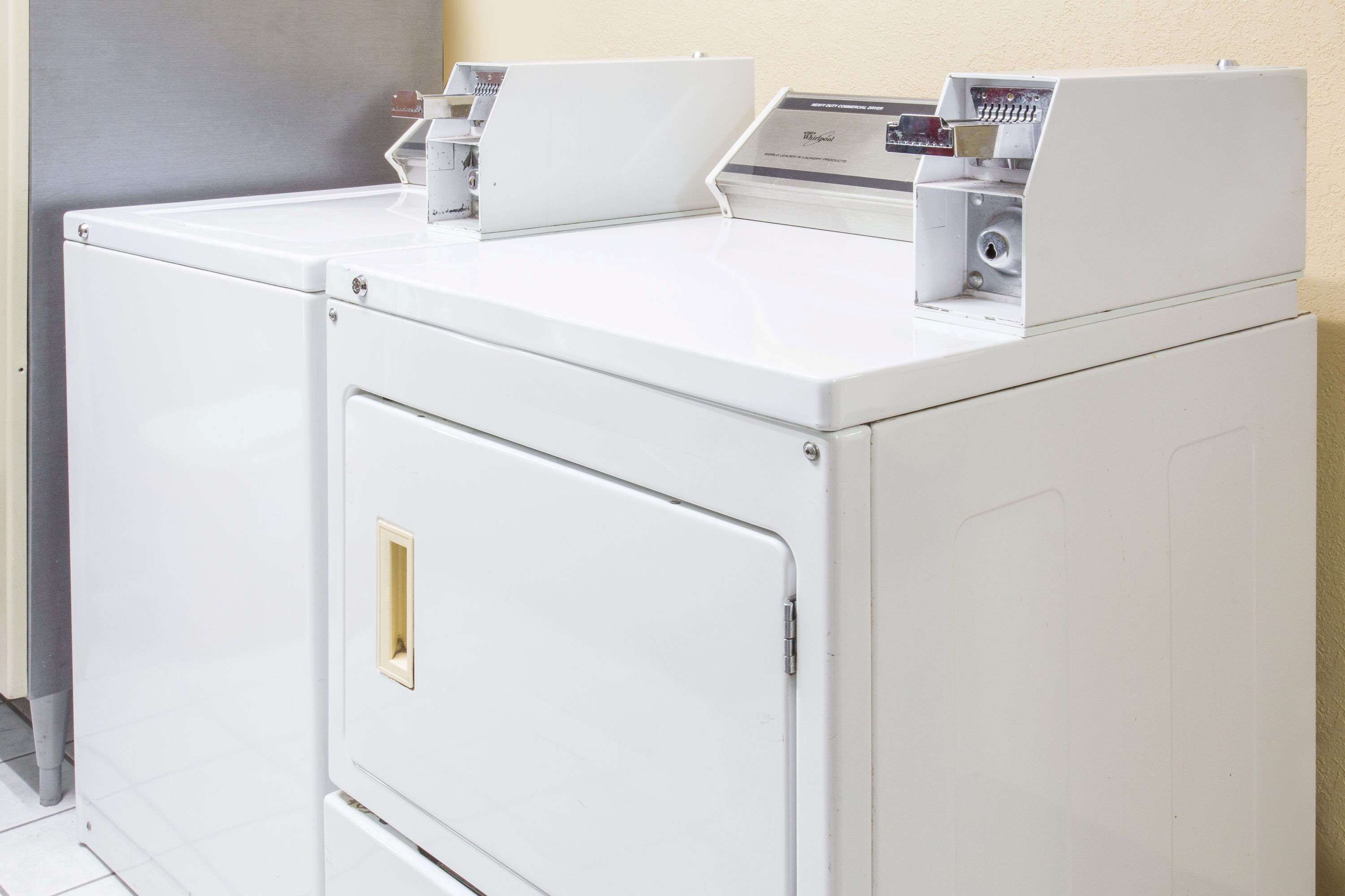 A front view of a white, compact, wall-mounted washer and dryer unit with a control panel on top.