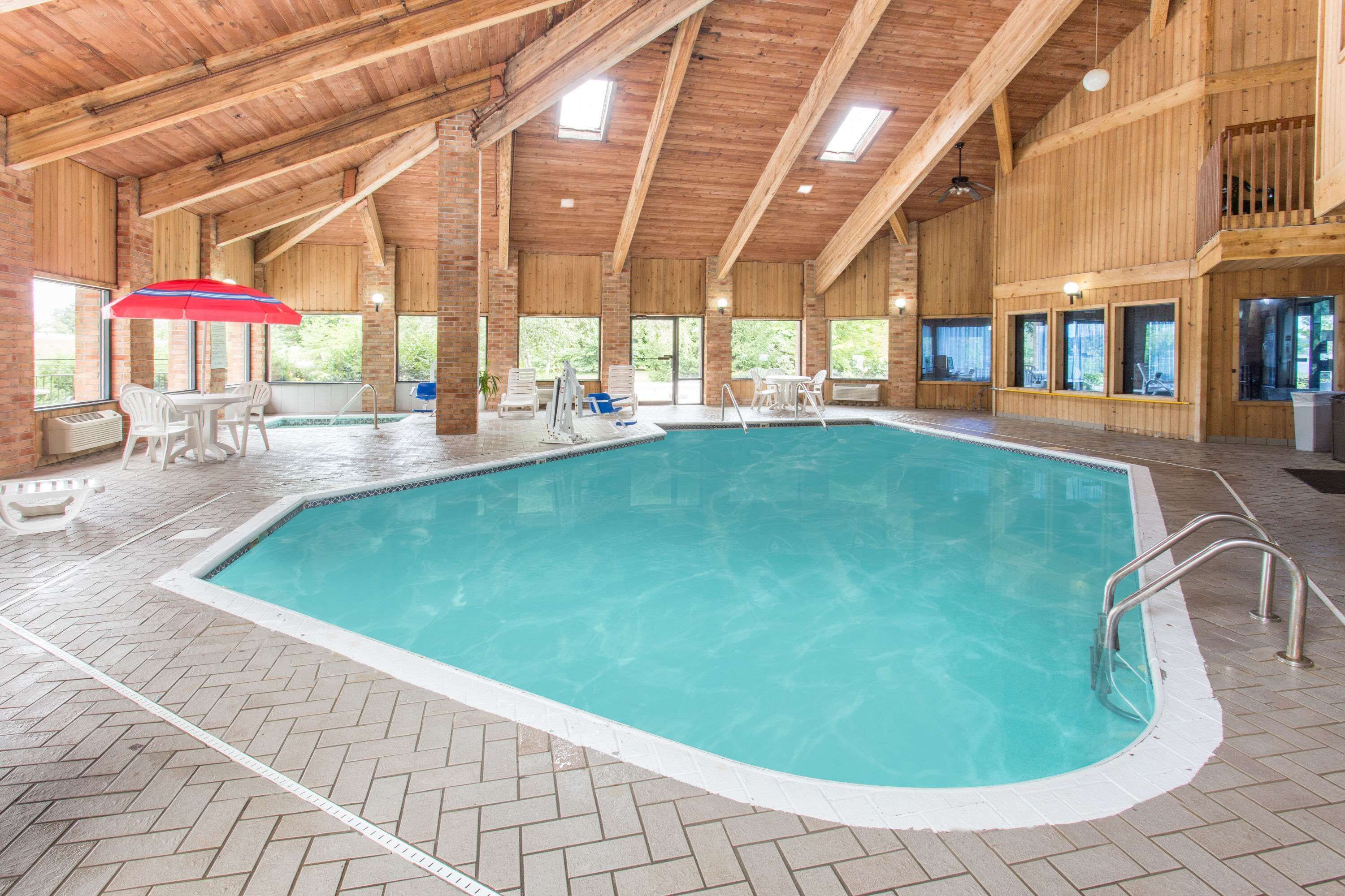 Una piscina interior con techo de madera y suelo de baldosas en patrón de espiga.