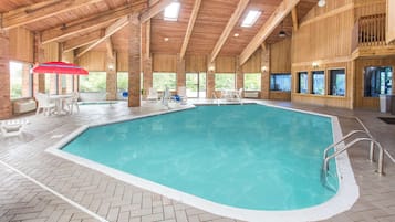 Una piscina interior con techo de madera y suelo de baldosas en patrón de espiga.