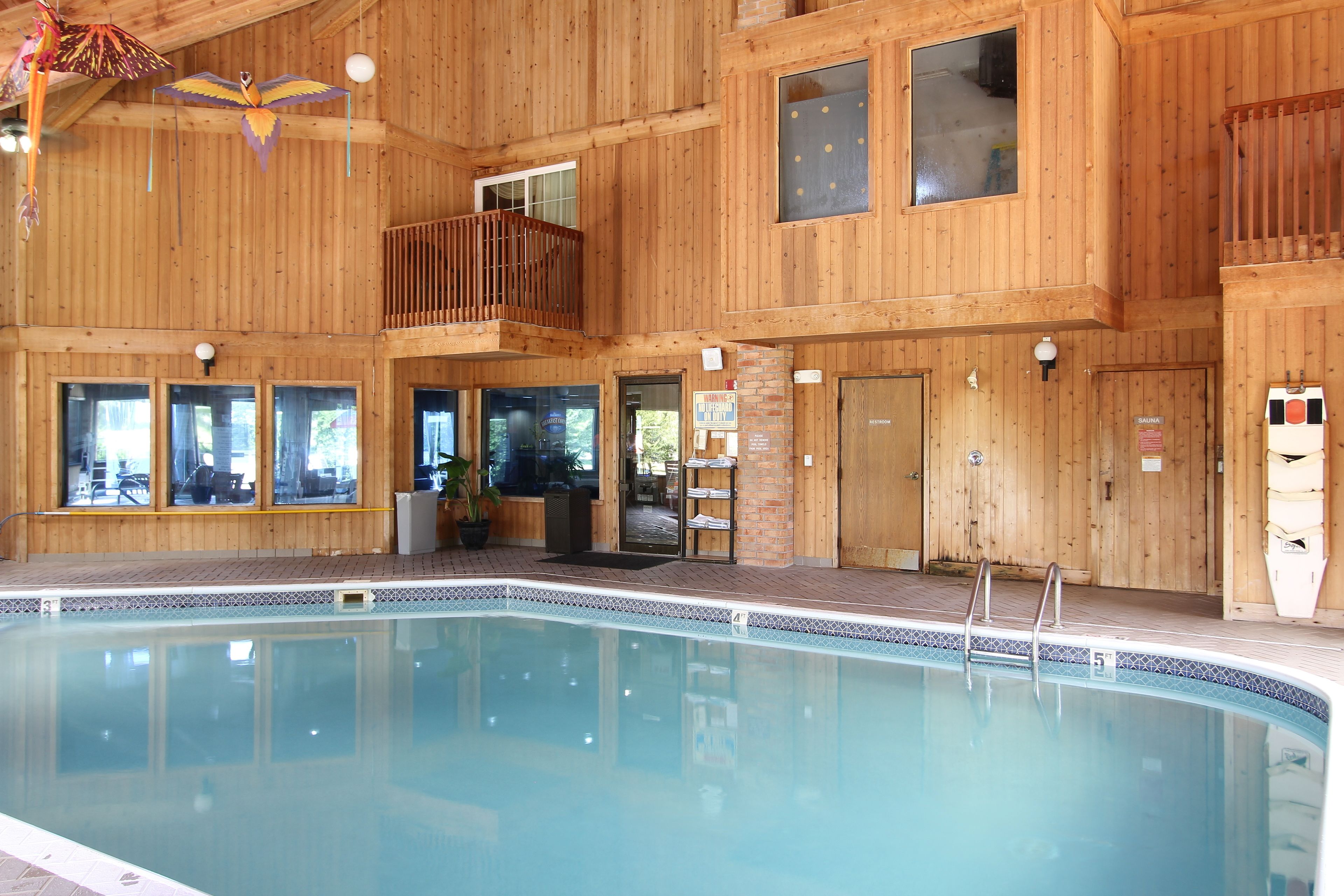 A wooden building with a pool, windows, and a balcony.