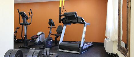 Un gimnasio con equipo de ejercicio, incluyendo una cinta de correr, una elíptica y pesas.