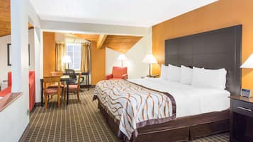 Habitación de hotel con una cama grande, un escritorio con una silla, dos lámparas y una ventana con cortinas.