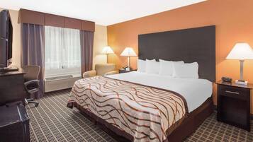 A hotel room with a large bed, two bedside lamps, a desk with a chair, a television, and a window with curtains.
